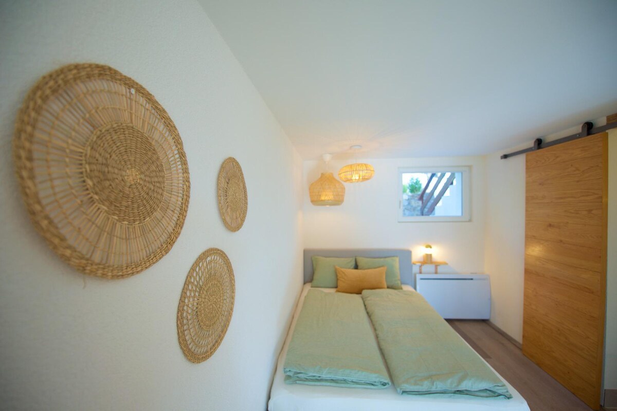 Мека и смирува соба, исполнета со светлина и облечена во природни тонови. Овде сѐ ве поканува на смиреност: дрвото, свежиот лен и оваа атмосфера толку мирна што ќе заспиете пред да изброите до три.