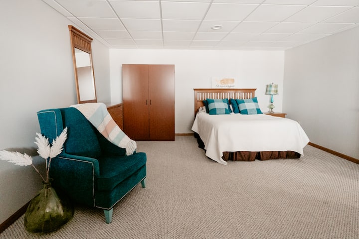 Comfy Queen bed, wardrobe, dresser, and cozy reading chair opposite the two twin beds.
