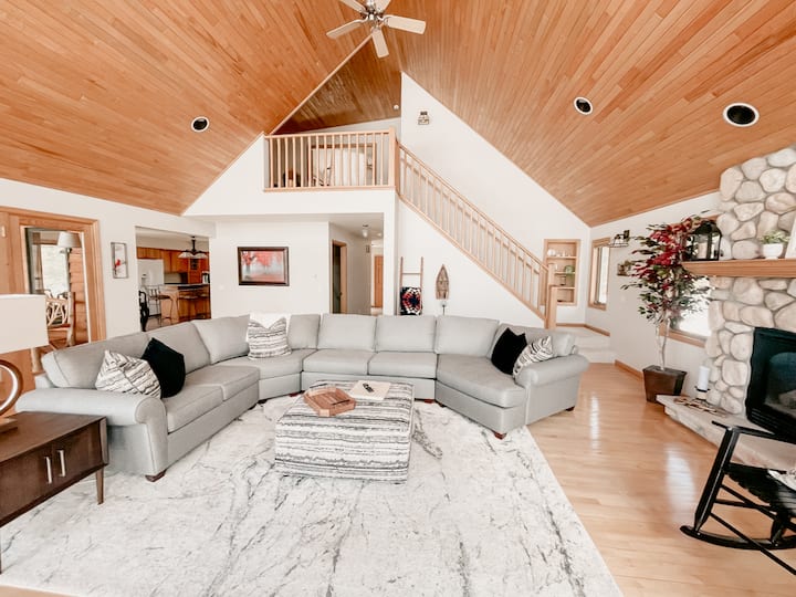 Main living area with high ceilings, large couch, electric fireplace, and view of Lake Superior. We also have a 55" Smart TV with Netflix loaded, and you have the ability to log in to your other streaming accounts. The couch has a queen pull out