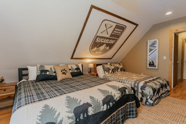 Hoofdslaapkamer met een kingsize bed en tweepersoonsbed, met usb en oplaadpunten aan elke kant van de bedden.