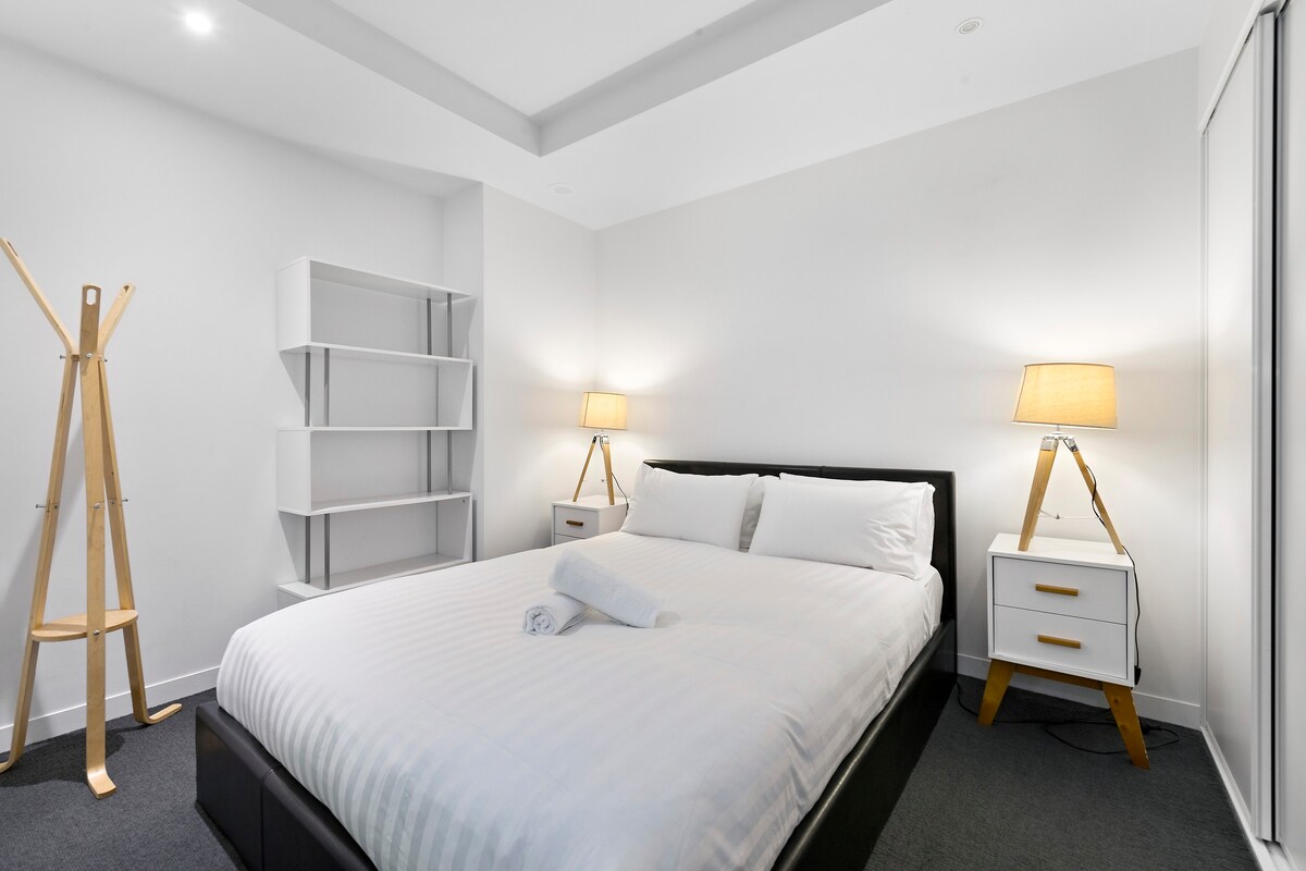 ห้องนอนแรกมีเตียงคิงไซส์หรูหราและโต๊ะข้างเตียงพร้อมโคมไฟอ่านหนังสือ