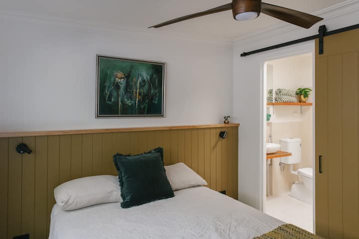 Dormitorio 3: cama tamaño queen. Asiento para guardar maletas y espacio para colgar. La habitación tiene una ventana, un ventilador y un baño privado con bañera.