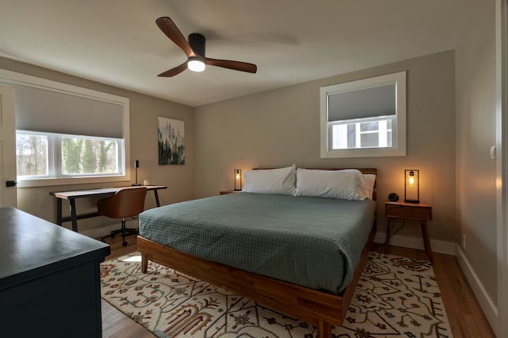 Main bedroom with king bed, nightstand lamps with USB ports, desk, TV, and private bathroom.
