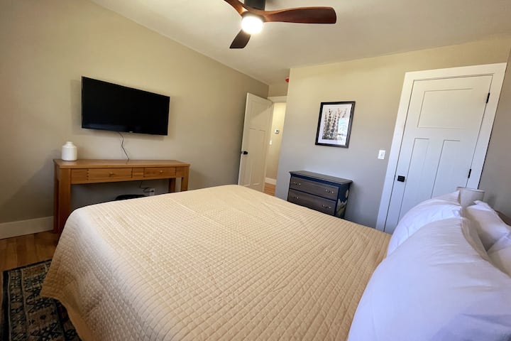 Queen bed with bedside lamps and Smart TV.