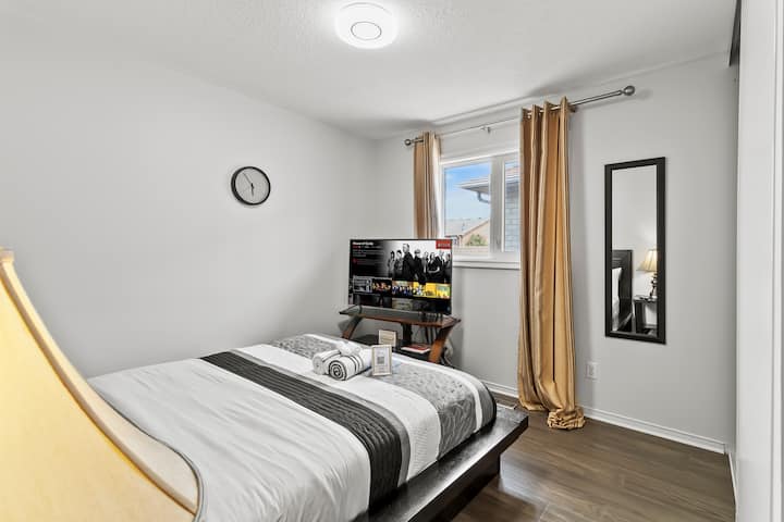 Spálňa s manželskou posteľou a 60-palcovou inteligentnou televíziou.