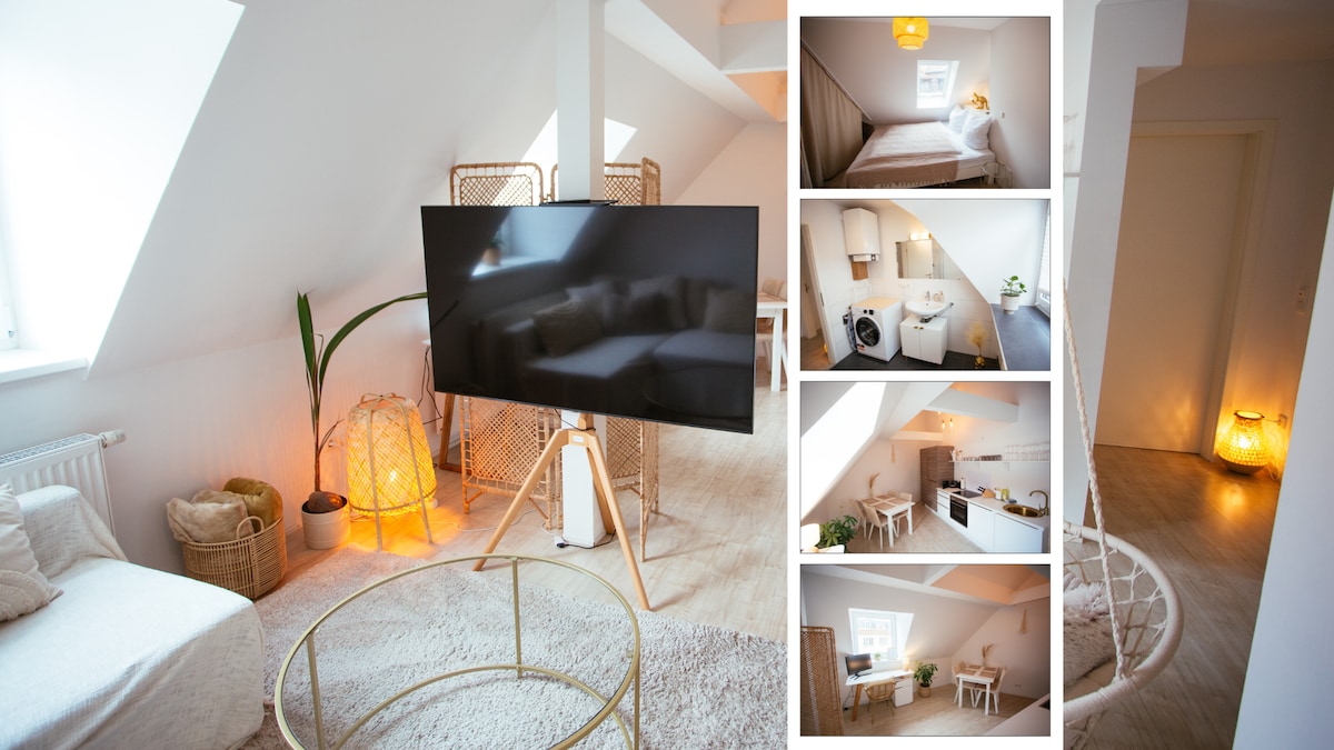 A modern living space is highlighted by a large smart TV positioned on a stylish stand. Soft lighting from a nearby lamp casts a warm glow, while a cozy seating area with neutral tones offers a relaxing atmosphere. The decor features minimalist design elements and natural textures.