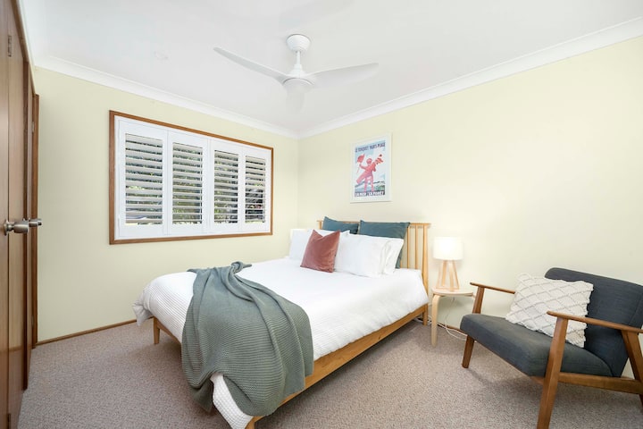 Chumba kikubwa cha kulala chenye nafasi kubwa chenye kitanda cha kifahari, hifadhi ya ukarimu na kiti cha kusomea chenye starehe, kuhakikisha ukaaji wenye utulivu.