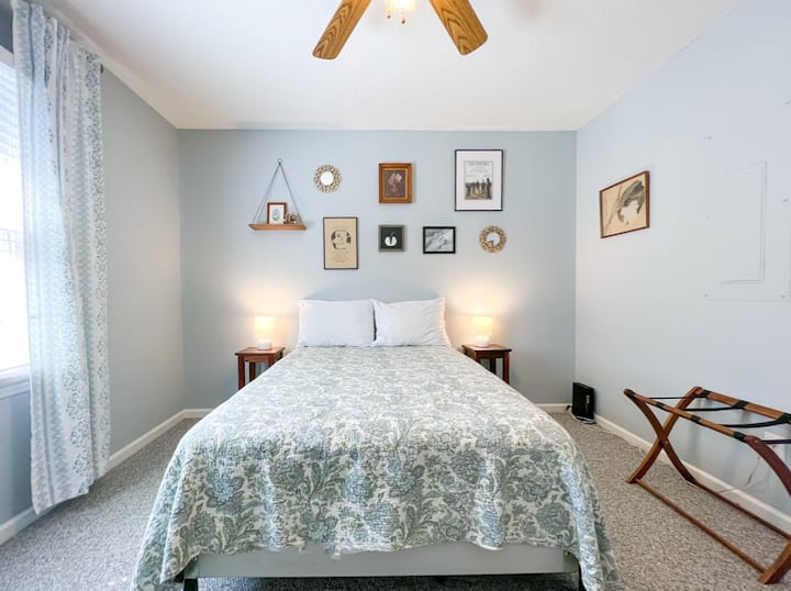 The first bedroom is light, bright, and airy with double bed, dresser, and luggage rack.