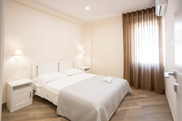 Muhtasari wa chumba ulio na kitanda cha watu wawili, taulo, meza za kulala 