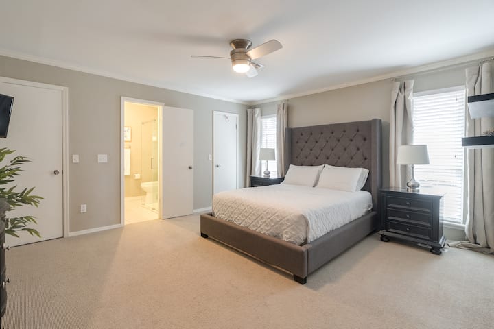 Main house primary bedroom with queen bed and attached bathroom and tv