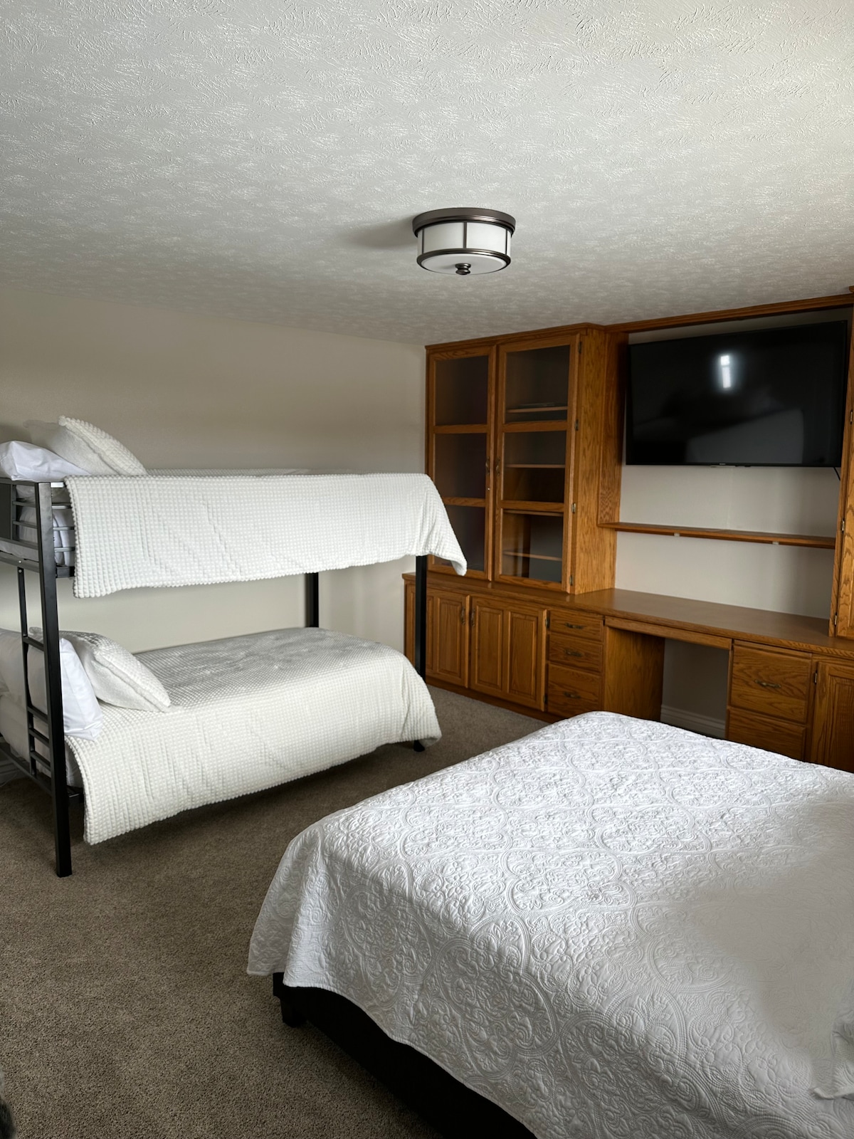 Dormitorio# 2, 1 cama queen, literas. 2 armarios estándar con perchas, cómoda de tamaño completo con espejo, televisor inteligente de pantalla plana, almohadas y mantas adicionales, mesas laterales de escritorio con lámparas y estación de carga.