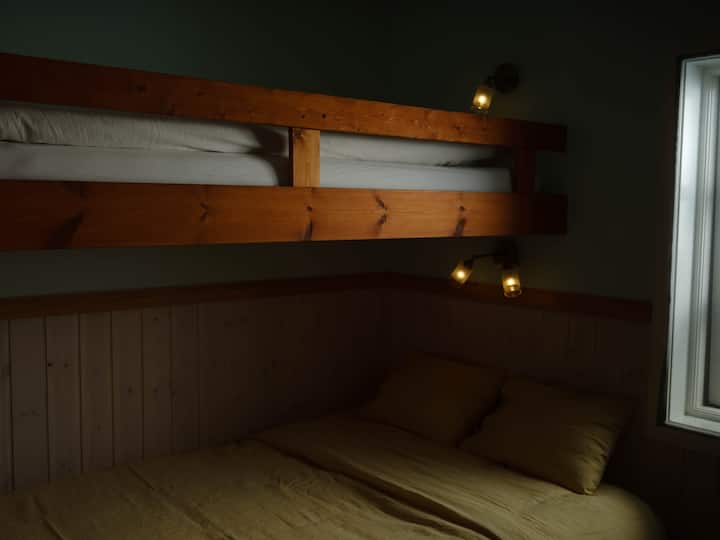 Bedroom with queen bed, single bunk bed, wardrobe and desk. 