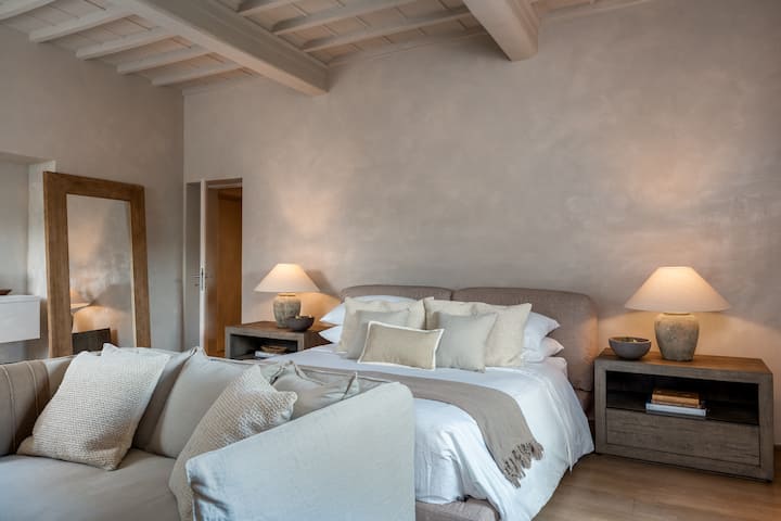 La suite principal Impruneta en O:live Villa Firenze cuenta con una cama tamaño king, una refinada sala de estar y cálidos pisos de madera, junto con vistas serenas a la campiña toscana y un diseño elegante y atemporal.