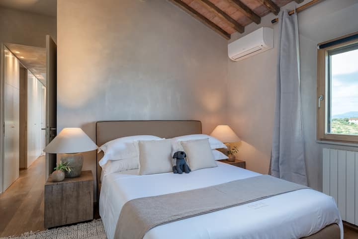 Las habitaciones Montefiore y Montelupo cuentan con camas tamaño queen, vigas de madera expuestas y vistas a la Toscana. Ubicados arriba, comparten un baño completo con ducha y bañera, completando un espacio privado de dos niveles.