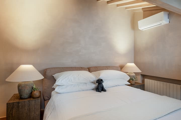 Il Solaio di Fiesole Loft – O:live Villa Palmas
Un acogedor dormitorio de estilo loft con tonos neutros cálidos, vigas de techo expuestas y una suave iluminación ambiental, diseñado como un refugio íntimo y tranquilo dentro de la villa.