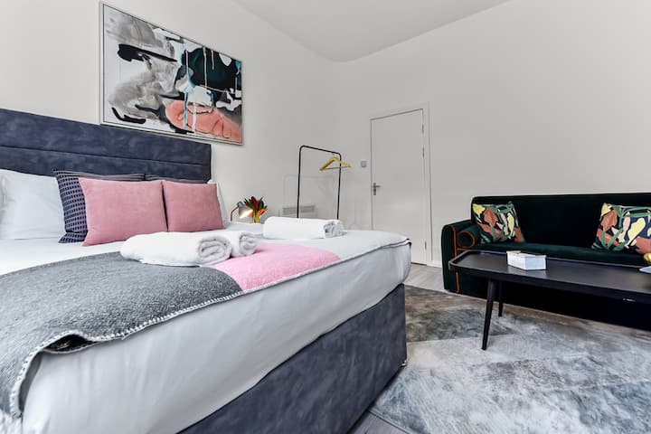 Una acogedora sala de estar en uno de los dormitorios cuenta con un elegante sofá cama, TV por cable y una tumbona. Disfruta de sábanas y almohadas frescas y suaves para disfrutar de la mejor experiencia de relajación.