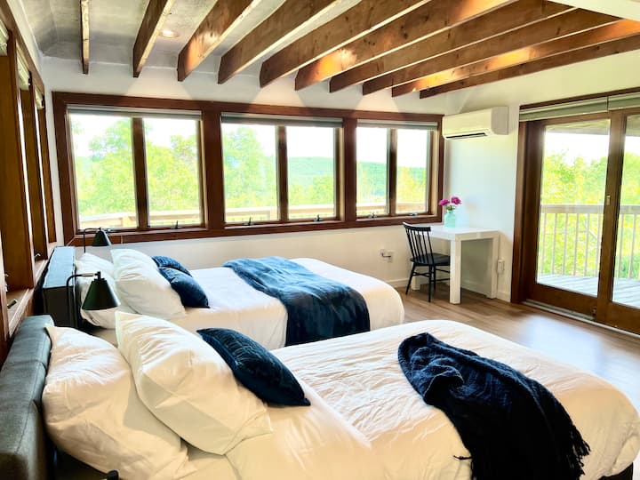 Main floor Bedroom #1 connects to a bathroom & a big deck. Walls of windows for stunning lake views. Sleeps 4: two singles (can make into a king bed) plus a queen. Enough space for air mattress and cribs. Desk and high speed wifi for remote working.
