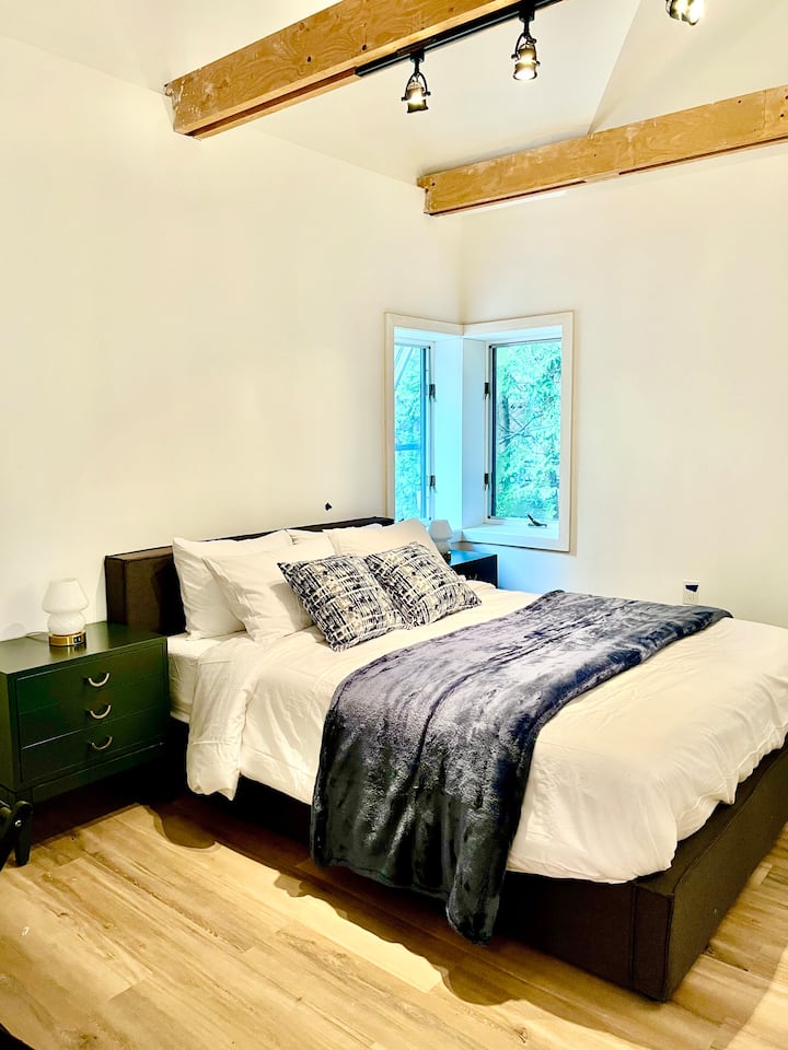 Main floor Bedroom #2 is a smaller room with a queen bed, a desk, and an en-suite bathroom. It comfortably fits a crib (full or mini size available).