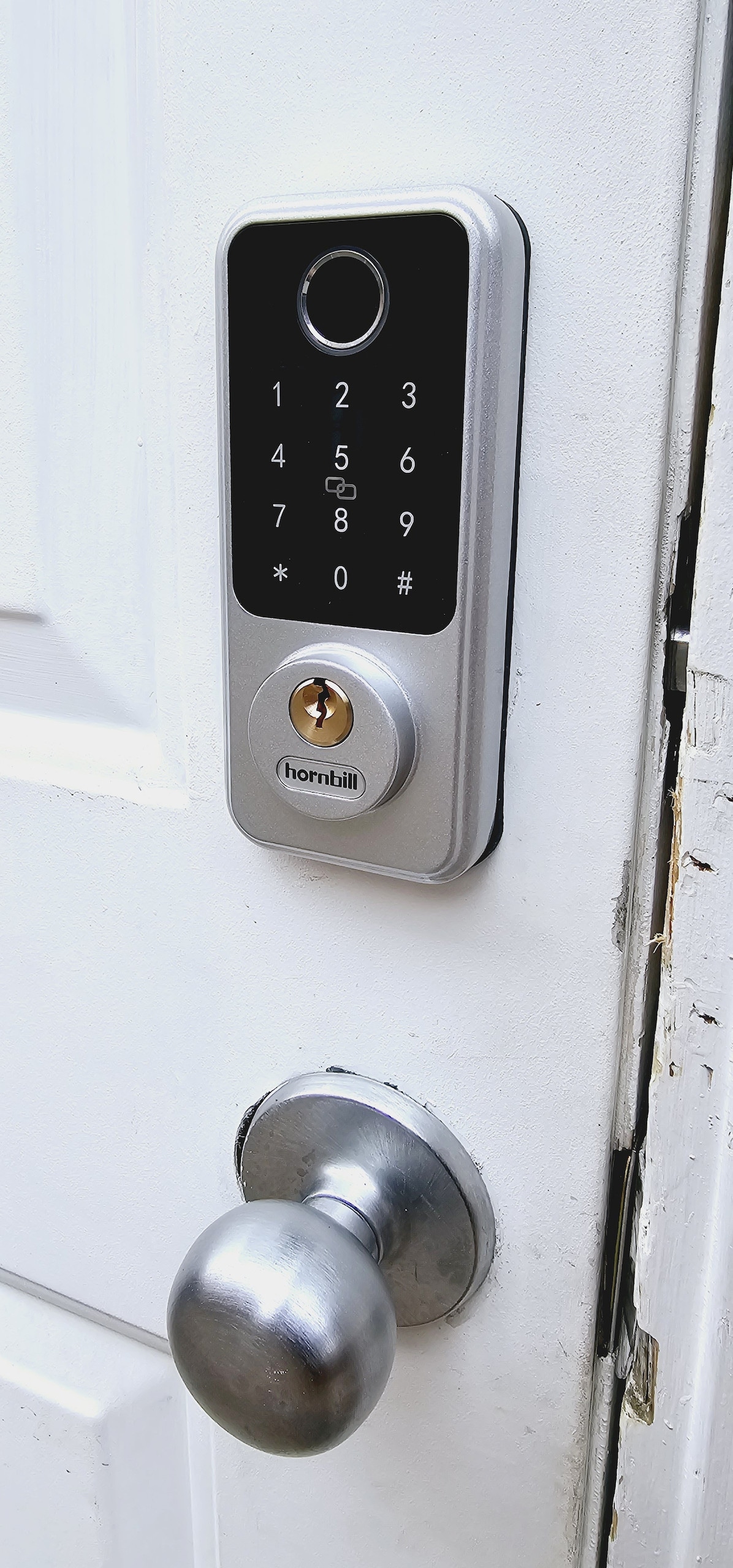 A digital keypad lock is mounted on a white door, featuring illuminated numbers for easy access. A round metallic doorknob is positioned below the lock, providing a practical entryway solution.