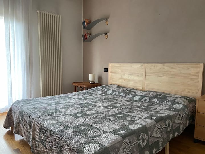 Camera padronale con letto matrimoniale in legno, camera dotata di comodino, armadio grande e scrivania di fronte al letto.