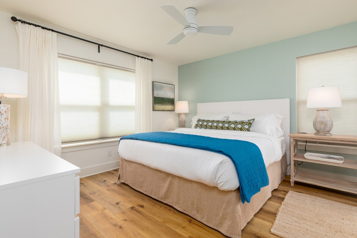 Primárna spálňa (na prízemí) ponúka manželskú posteľ, dizajnové vankúše a posteľnú bielizeň, pohodlnú nabíjaciu zásuvku, inteligentnú televíziu a vlastnú kúpeľňu.  Posuvné sklenené dvere vedú na bočnú terasu.  Krásne podlahy na prvom poschodí.