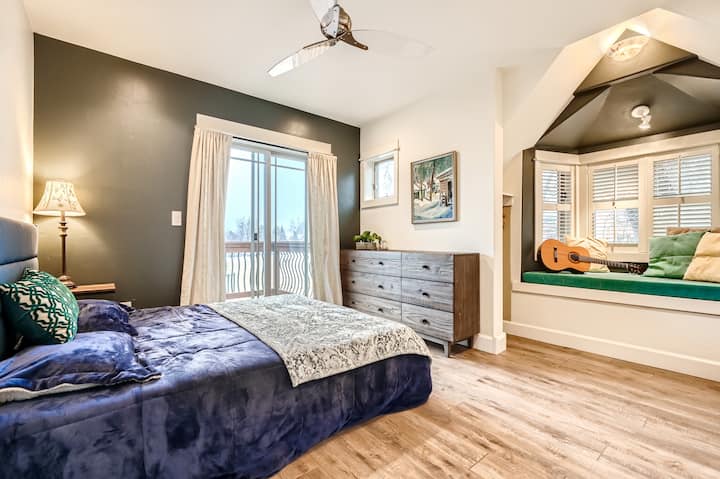 Dhoma e dytë e gjumit në katin e sipërm me kënd leximi, ventilator tavani dhe hyrje në verandë.