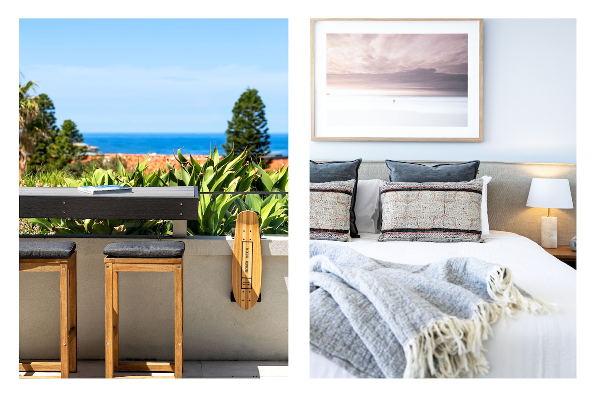 A large terrace offers unobstructed ocean views, furnished with wooden stools alongside a sleek bar area and lush greenery below. The second image features a neatly made bed adorned with textured pillows and a soft throw blanket, with natural light gently illuminating the space.