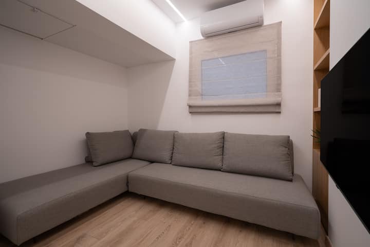 Une chambre avec un grand canapé d'angle et une grande télévision connectée