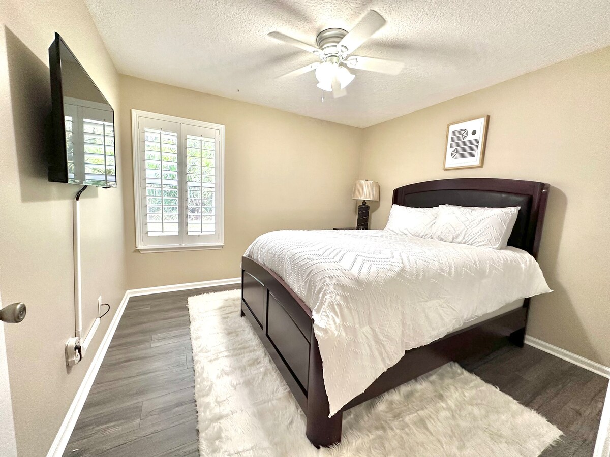 Queen size guest room with elevated bed and TV