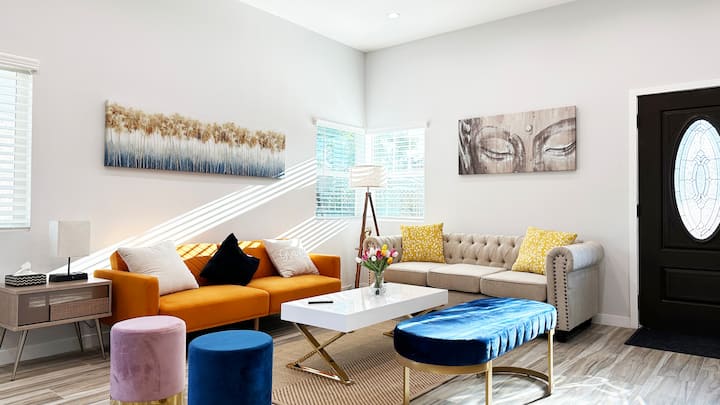 Светла всекидневна с цветна подредба за сядане и 65 - инчов телевизор, идеални за забавление.