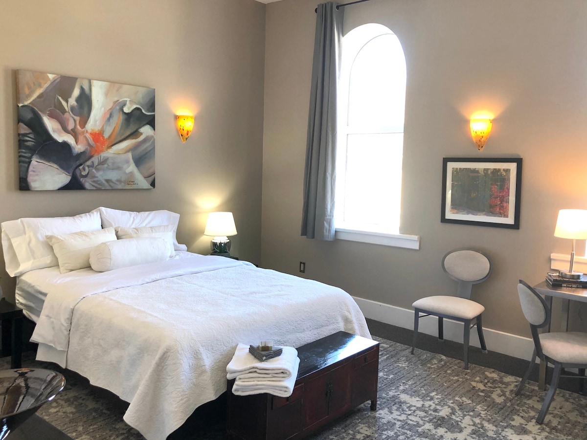 Veľká izba s posteľou s počítačovým stolom, manželskou posteľou a televízorom s plochou obrazovkou. Dve okná s 8-palcovými oknami ponúkajú pekný výhľad na kostolnú vežu z roku 1800.