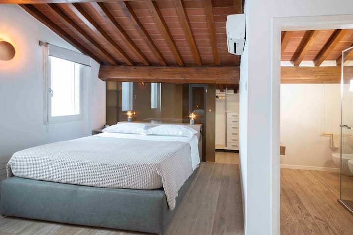 Velika spavaća soba otvorenog tipa s najsuvremenijim klima-uređajem instaliranim u lipnju 2023. U pozadini, ugradbeni ormar. Na desnoj strani je kupaonica s temom „od kamena i drveta”.