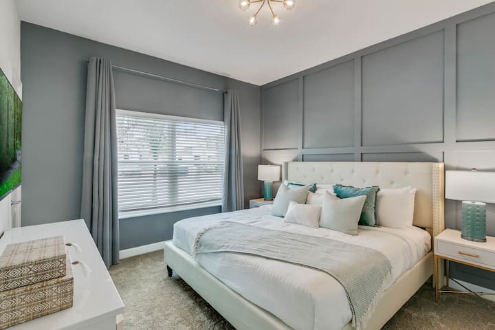 ห้องนอนใหญ่ชั้นล่างพร้อมเตียงคิงไซส์สมาร์ททีวีติดผนังและห้องน้ำเต็มรูปแบบอยู่ติดกัน 