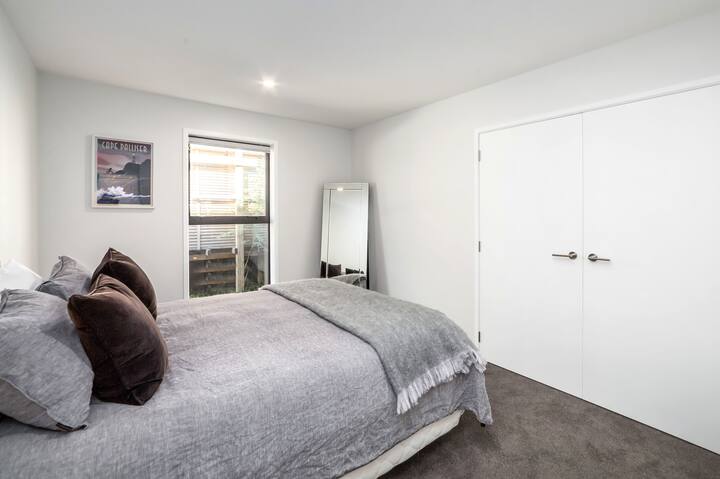 El segundo dormitorio con su cama tamaño queen, acompañado de un gran espejo y un amplio espacio de almacenamiento.