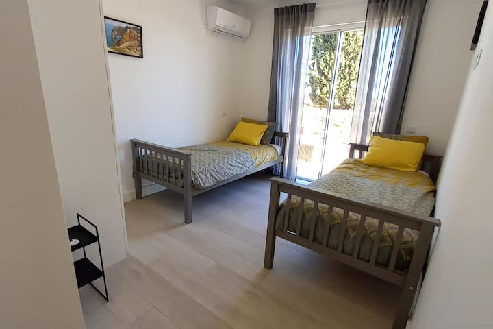 ห้องนอนพร้อมเตียงเดี่ยว 2 เตียงและเครื่องปรับอากาศ