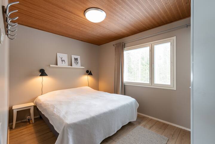 Chumba cha kulala cha chumba cha chini kina kitanda pana cha sentimita 180 na kabati. Madirisha yanayoangalia mazingira ya asili.