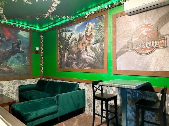 Влезте в тази игрална зала от Джурасик, където буйни светодиодни лиани покриват яркозелен таван, а по стените се издигат огромни стенописи на тиранозаври. Предизвикайте приятелите си на въздушен хокей, отпуснете се на плюшената зеленикава секция – вашият праисторически рай за игри ви очаква!        