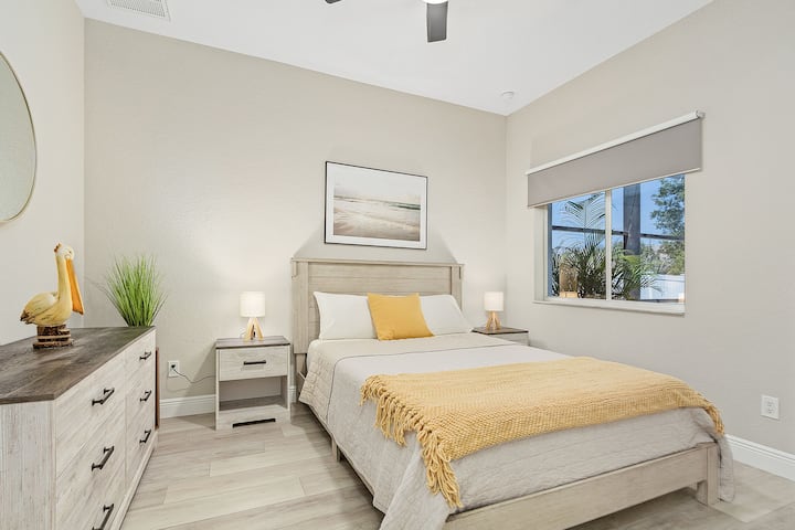 Chic queen bedroom accented by tropical artwork and soft textiles – ideal for couples or friends.