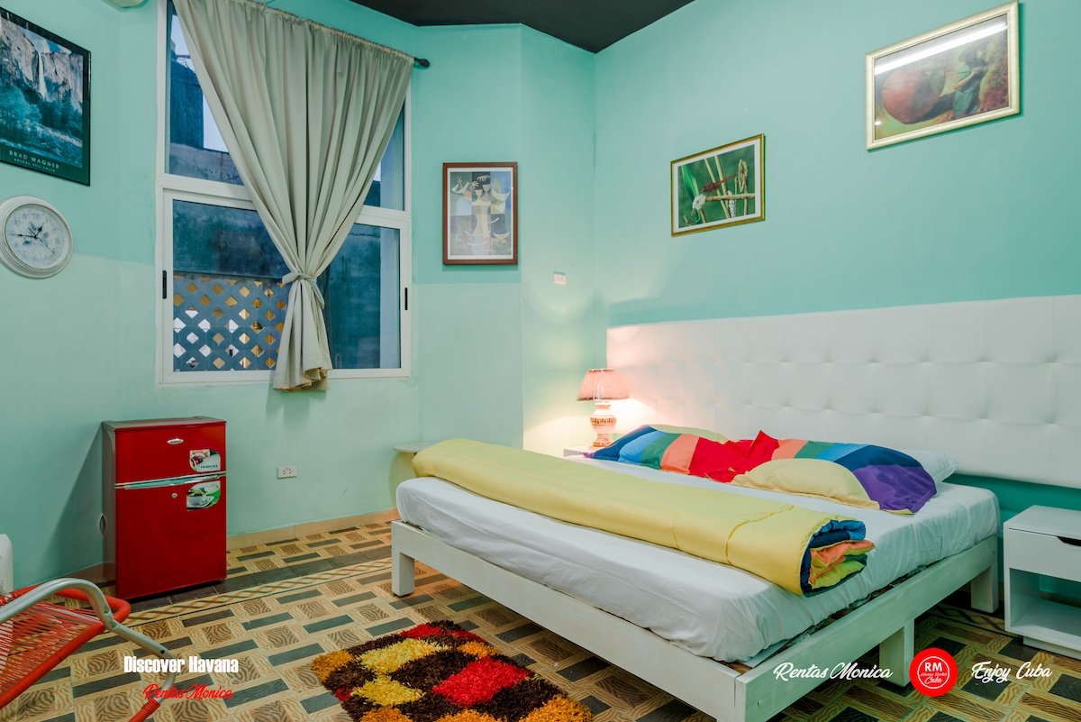 Dormitorio #7 con cama tamaño king, aire acondicionado, baño privado, pequeña sala de estar, minibar y TV.
