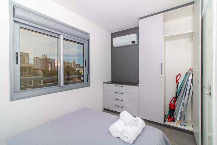 غرفة بسرير مزدوج وعناصر دعم مثل الدرج والمكنسة الكهربائية وطاولة الكي