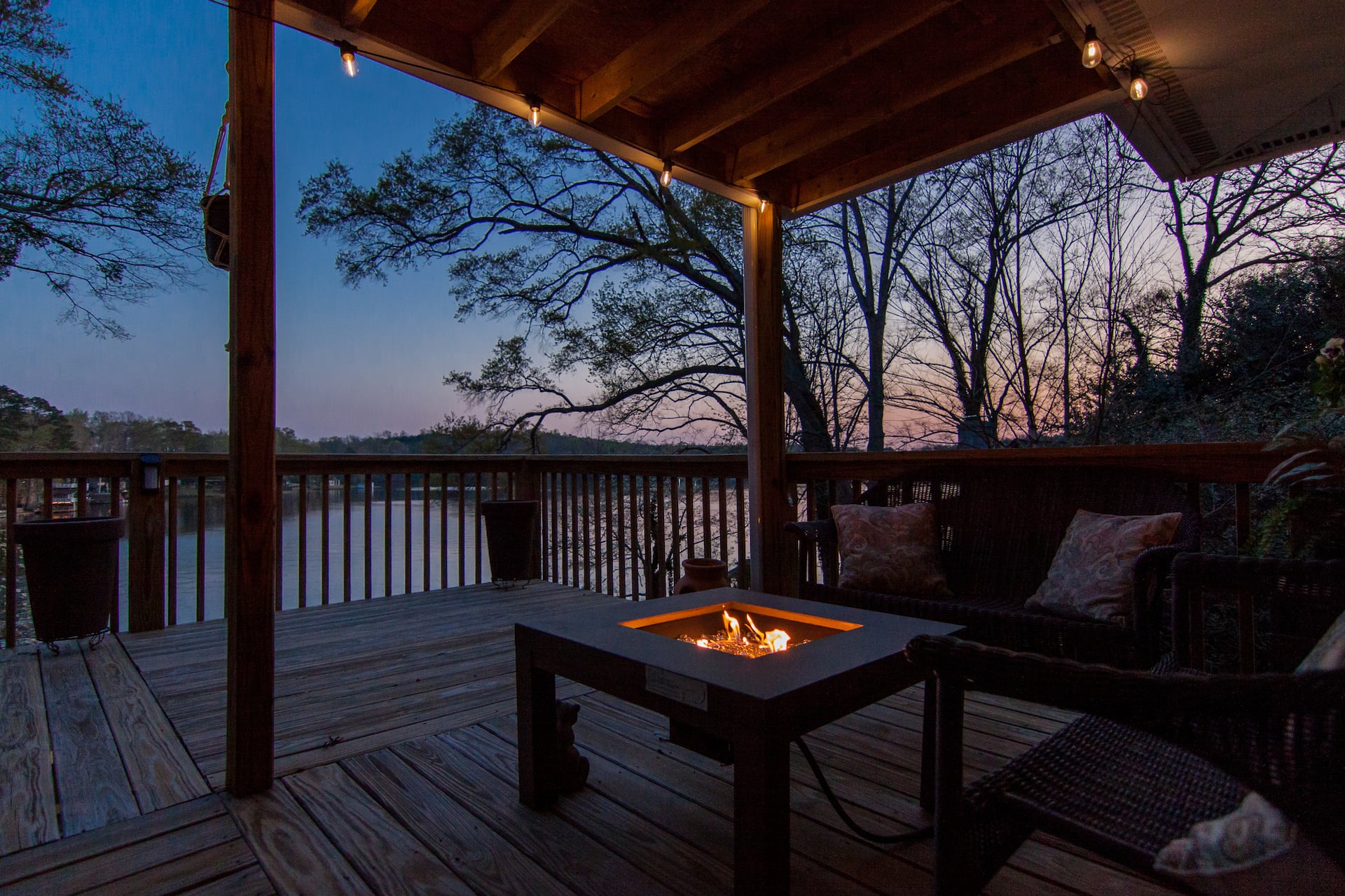 Covered deck with fire pit table overlooking Broadway Lake at dusk