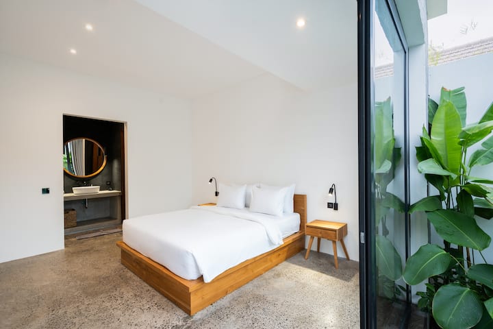 Un dormitorio luminoso y espacioso con grandes ventanales que ofrecen vistas al jardín circundante.