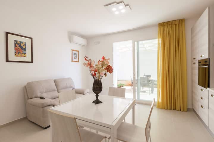 Sala de estar con sofá, Smart TV, comedor con mesa y sillas y cocina abierta y cocina abierta.