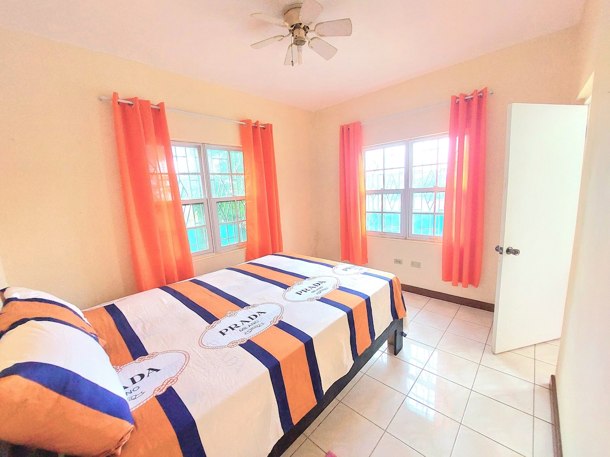 De vierde slaapkamer met een queensize bed bevindt zich op de begane grond naast de eet- en woonkamer. Het heeft een grote kast en een eigen badkamer (nummer 3). Plafond- en sokkelventilatoren koelen de kamer af. Roosters op elk raam zorgen voor veiligheid.