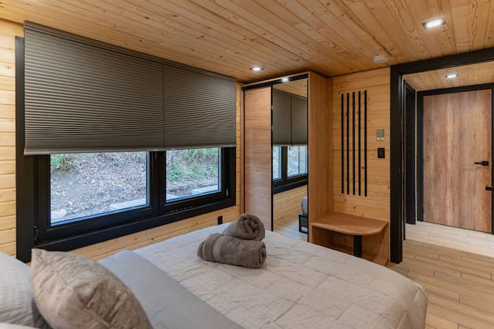  Spálňa na prízemí je vybavená pohodlnou manželskou posteľou s mäkkou posteľnou bielizňou, úložným priestorom na nočný stolík a okolitým osvetlením, čo vytvára útulné útočisko na pokojné noci.
