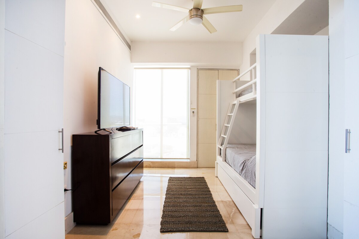 غرفة نوم مع سرير بطابقين ومروحة سقف ومكيف هواء وتلفزيون ذكي 