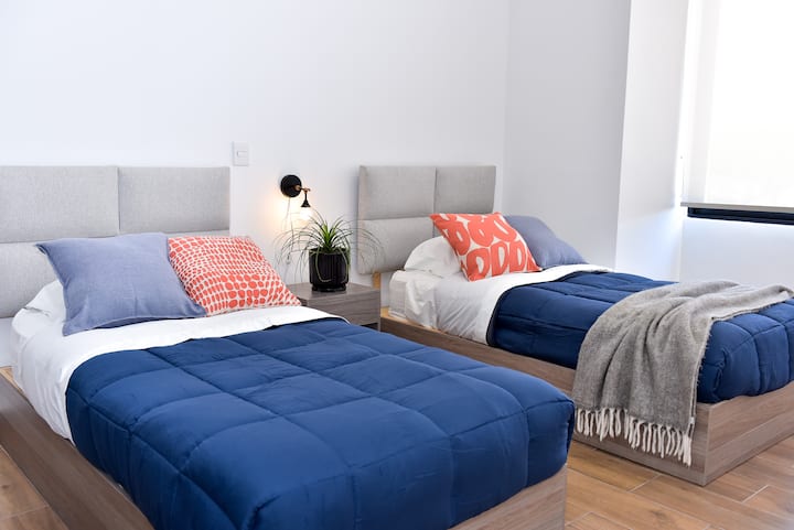 Chumba cha kulala cha pili cha ghorofa kilicho na vitanda viwili pacha, kabati na dawati la kazi.