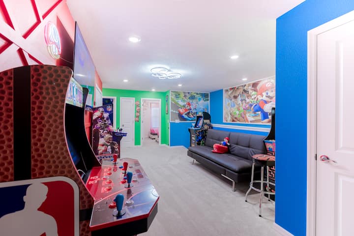Rritu në një dhomë emocionuese lojërash Super Mario! Kjo hapësirë përmban makina arcade, një tavolinë futbolli, art muri me tematikë, drita neoni, një televizor të madh, dekor argëtues dhe një atmosferë të gjallë lojërash — të përsosura për një aventurë gjithëpërfshirëse në Mbretërinë e Kërpudhave me argëtim