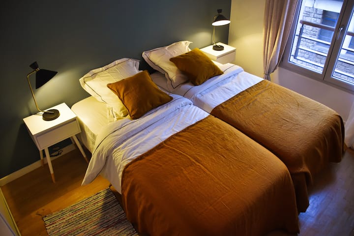 غرفة نوم ثانية مع سريرين مفردين مريحين إضاءة دافئة، والكثير من التخزين والستائر الكهربائية.