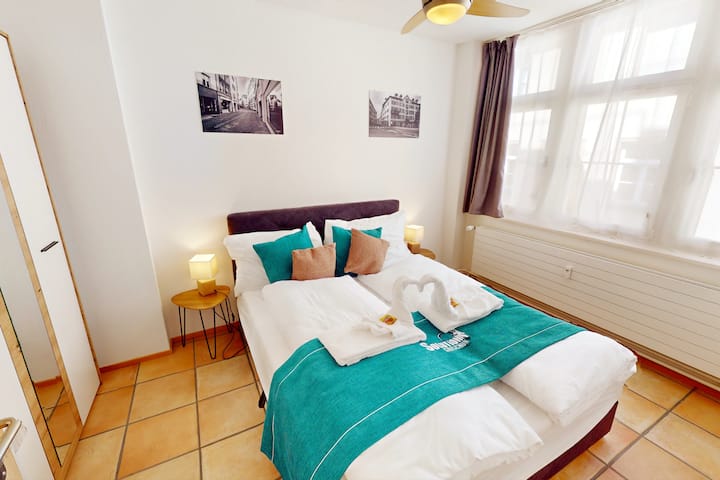 Útulná pružinová posteľ (160 x 200) v priestrannej spálni s veľkou šatníkovou skriňou a osviežujúcim stropným ventilátorom pre dokonalé pohodlie pri spaní.